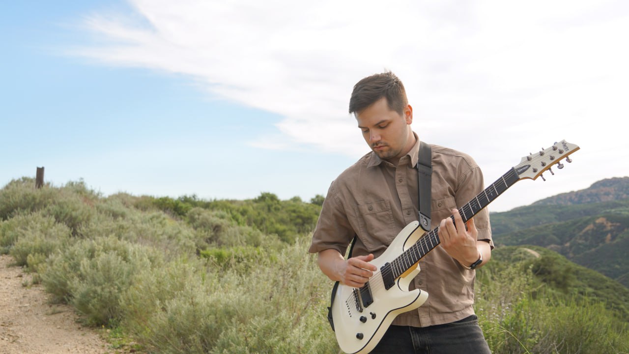 Thaddeus Arndt playing acoustic guitar outdoors in the LA hills
