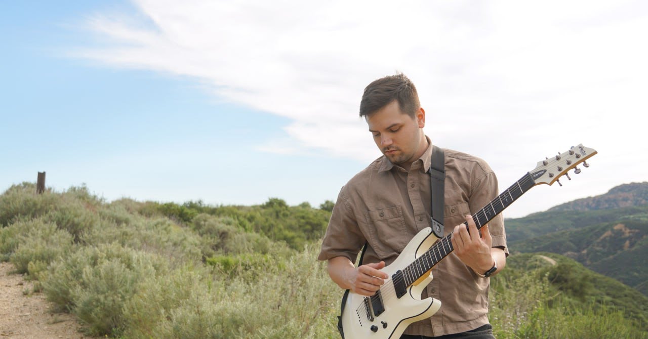 Thaddeus Arndt playing electric guitar on a canyon trail