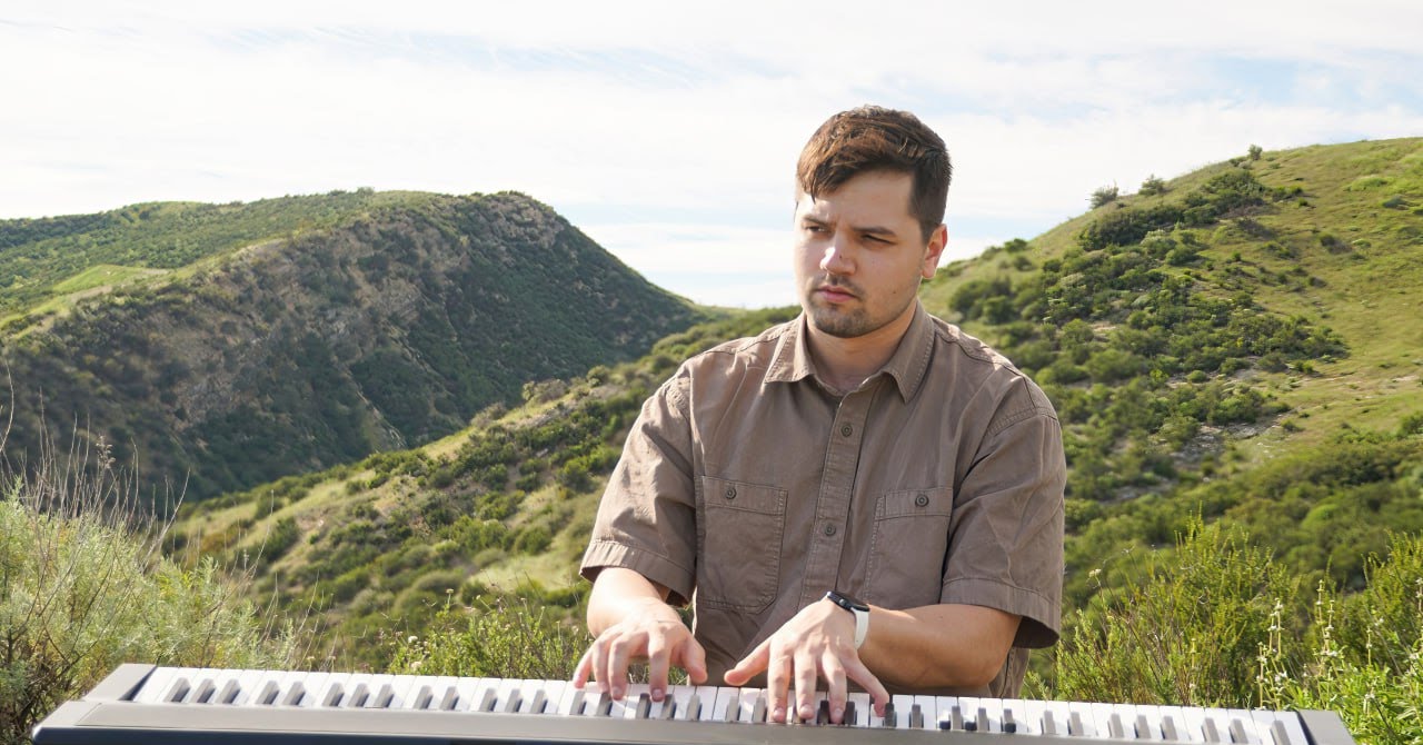 Thaddeus Arndt playing keyboard on a green hillside in Los Angeles