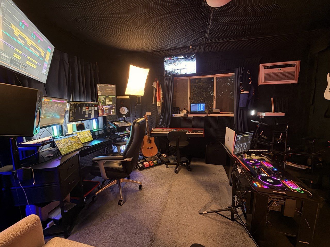 Behind the desk — multi-monitor production setup, Pioneer DJ controller, guitar, keyboard